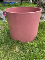 Angled view of pink cylindrical porcelain planter on grass