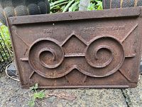 Front of ornate cast iron panel showing scroll design and embossed patent marking