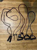 Overall shot of two leather ropes and two resistance tubes laid out on floor