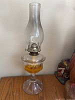 Full view of oil lamp showing chimney, font with fuel, and pedestal base