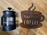 French press and metal sign side by side