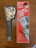 Bostitch H2B stapling hammer beside its original box showing full tool and packaging