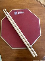 Front view of Evans RealFeel red rubber practice pad with drumsticks on top
