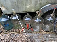 Row of five carboys with corker and spoon visible