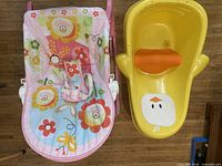 Infant rocker and yellow duck bathtub side by side