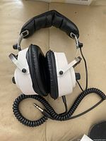 Full view of folded Jana BJ-2000 headphones showing earcups, headband padding and coiled cable with 1/4-inch plug
