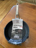 Top view showing speckled interior, stainless handle, and front of Heritage The Rock label
