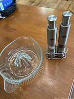 Stainless steel grinders in stand beside glass juicer on tabletop