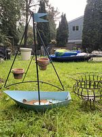 Full view of boat-shaped plant stand with three hanging pots and round basket stand beside it