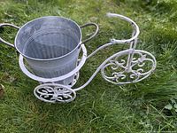 White metal bicycle plant holder with galvanized pot resting on grass
