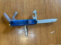 Knife with several tools open showing large blade, opener tools and wood saw