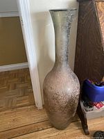 Full view of tall glass vase standing on floor