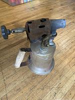 Left side view showing brass tank, wooden handle, steel burner head