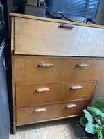 Full view of desk showing drop-front closed and three drawers