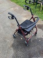 Side view of burgundy rollator walker showing seat, bag, wheels, and brakes