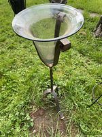 Full view of wrought iron plant stand with clear glass bowl outdoors