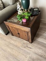 Side table with glass top inset, plant and phone on top