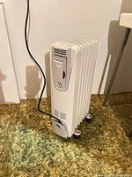 Full view of DeLonghi heater showing fins, wheels, cord