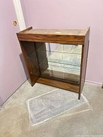 Front view of wood veneer display cabinet showing two glass shelves and mirrored back