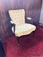 Full view of beige tufted armchair on red carpet