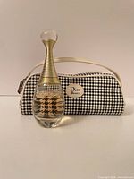 Fragrance bottle standing before houndstooth pouch