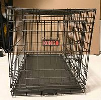 Front view of Kong wire dog crate showing logo and tray