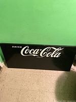 Full view of rectangular black Coca-Cola sign