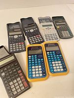 Group shot of seven calculators laid out on table