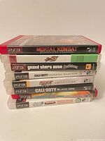 Stack of eight PS3 game cases showing spines and titles