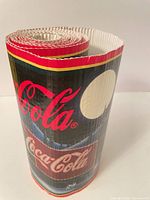 Rolled corrugated Coca-Cola poster showing logo and colour border