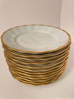 Stack of 12 white porcelain plates with gold rims