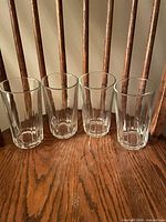 Four clear glass tumblers on wooden chair seat