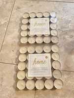 Two sealed packs of Home unscented tealights