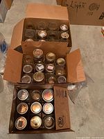 Two boxes filled with assorted clear glass canning jars of different sizes