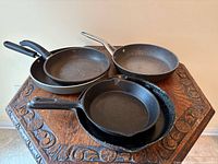 Group of five frying pans on a table
