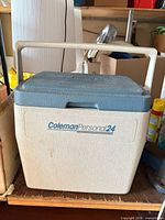Front view showing Coleman Personal 24 graphics, blue lid, carry handle