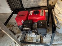 Front angled view of Honda EZ1800 generator showing engine, red fuel tank, control housing, and frame