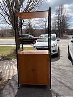 Front view of shelving unit showing metal frame, two open shelves, closed cabinet