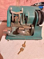 Front view of Keil key cutting machine showing vises, cutting area, side brush and two included keys