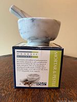 White marble mortar and pestle positioned on product box showing dimensions and capacity