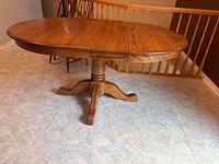 Oval oak pedestal table, leaf seams visible