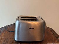 Front view of stainless Oster 2-slice toaster showing slots and logo