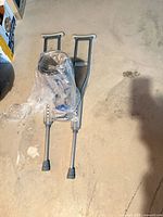 Pair of adjustable aluminum crutches with boot bagged together on floor