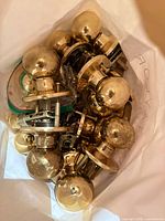 Bag containing multiple polished brass door knobs with hardware components