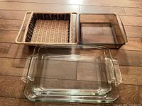 All three Pyrex dishes and wicker holder laid out on wood floor