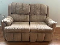 Front view of tan fabric reclining loveseat