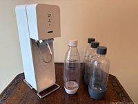 Front view of SodaStream maker, three grey-cap bottles, one white-cap bottle