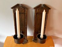 Front view of both wooden wall sconces with candles inserted