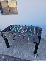 Three-quarter view of entire foosball table showing playfield, rods, legs