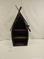 Front view of boat-shaped wall shelf showing three shelves and crossed oars